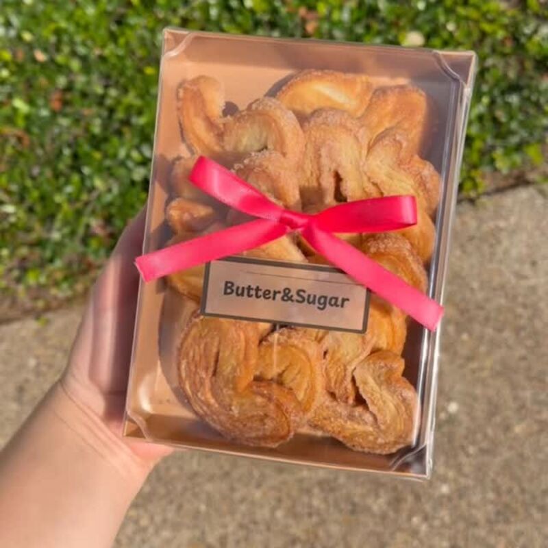 Una caja de orejas cerrada con moño rosa y la etiqueta de Butter and Sugar