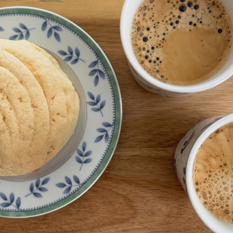 Una concha en un plato de talavera azul, junto a dos tazas de café